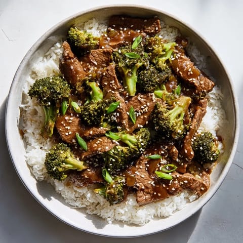 Hot wok stir-fry of Beef and Broccoli, garlic and ginger aromatics, glossy sauce clinging to sliced beef and green florets.