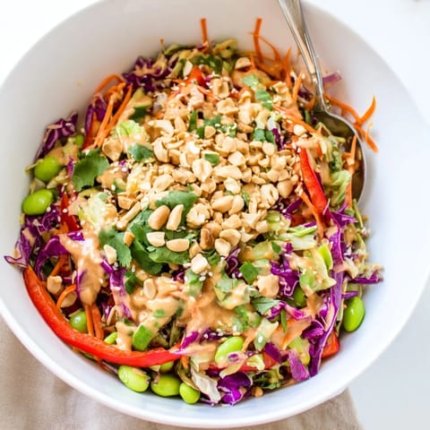 Colorful platter of fresh Crunchy Thai Peanut Salad garnished with peanuts and lime wedges for a zesty serving suggestion.  