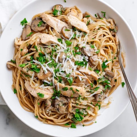 A close-up of Creamy Mushroom Chicken Spaghettini with sautéed cremini mushrooms, garlic, and melted Parmesan in a velvety sauce.