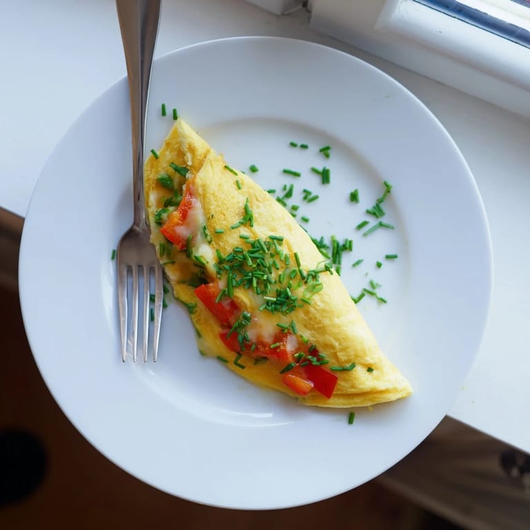 Cheesy omelet with bell peppers and spinach, steam rising from the golden, fluffy eggs on a skillet.