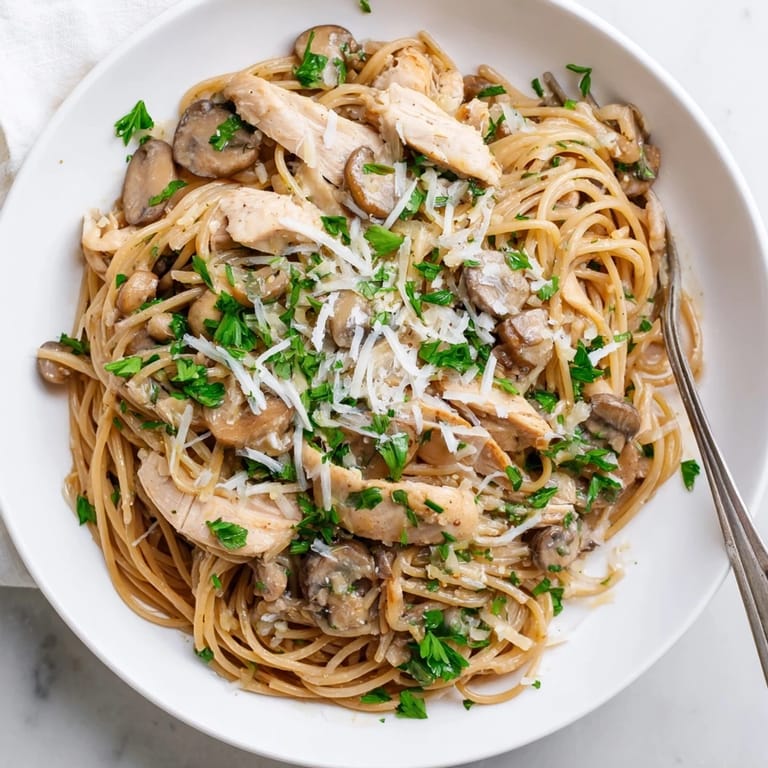 A close-up of Creamy Mushroom Chicken Spaghettini with sautéed cremini mushrooms, garlic, and melted Parmesan in a velvety sauce.