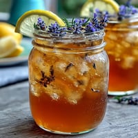 Refreshing lavender honey lemonade pitcher with ice, garnished with lemon slices and fresh lavender sprigs.