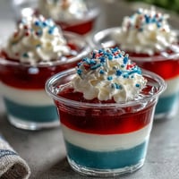 Festive 4th of July Firecracker Jello Shots bursting with fruity flavor atop white layer.